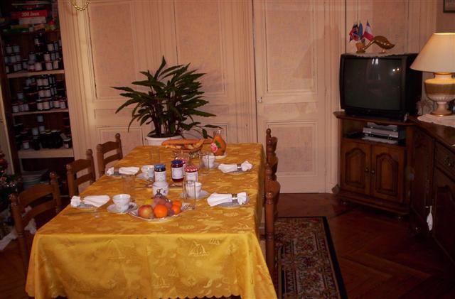 Table du petit-déjeuner dressée avec une nappe jaune, fruits, confitures et produits normands, Les deux chênes